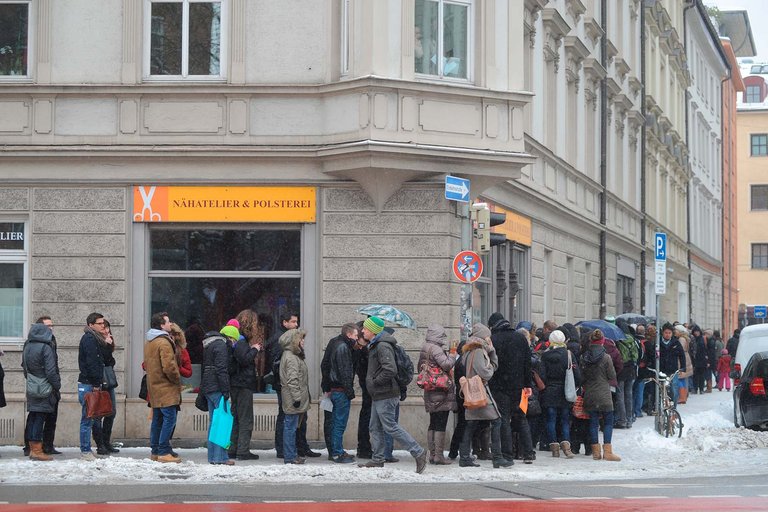 Wohnungssuchende in einer Schlange auf der Straße für eine Wohnungsbesichtigung