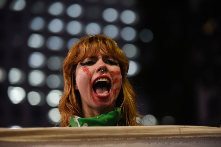 Gegen Gewalt protestierende Frau mit dem Abdruck einer roten Hand im Gesicht